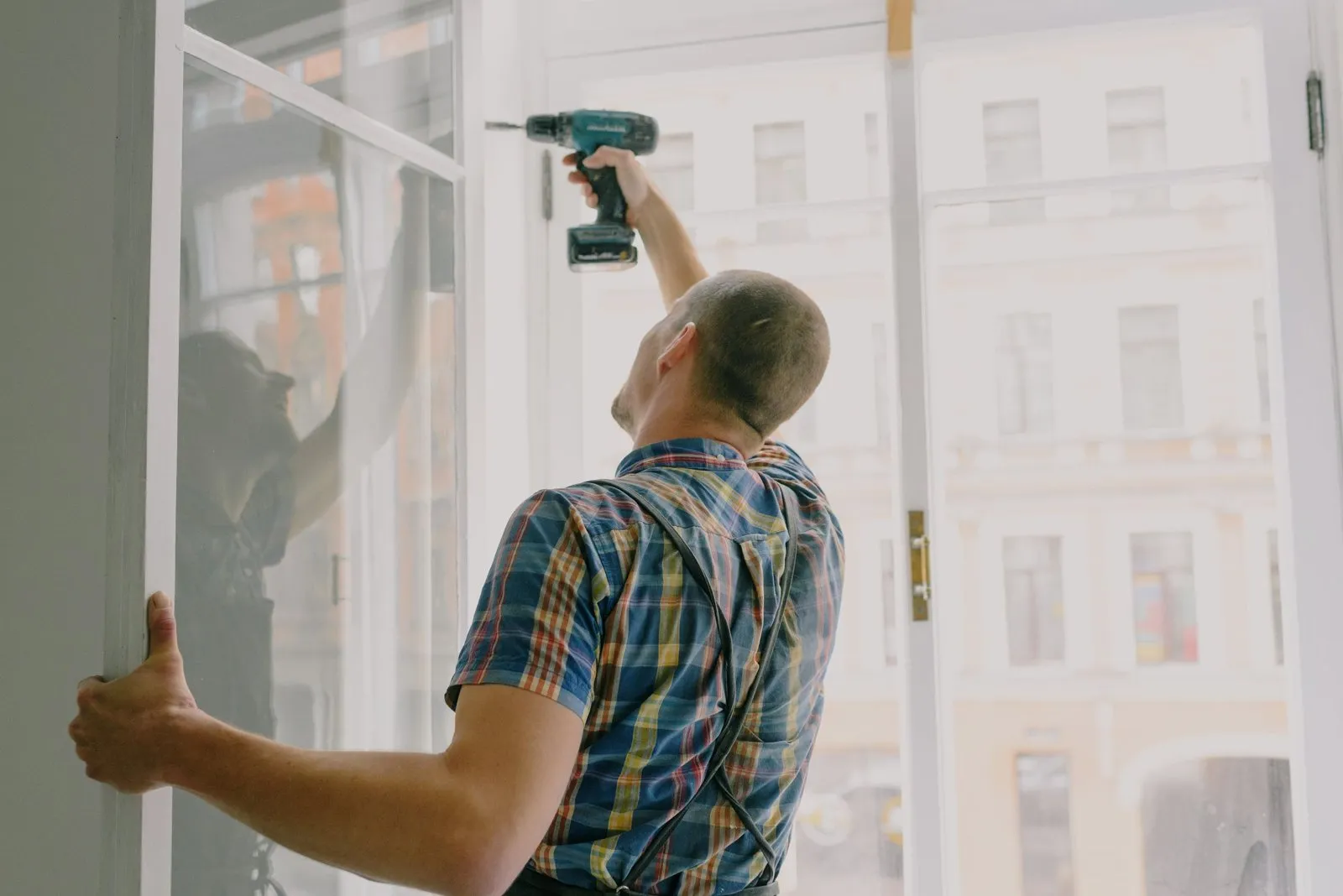 Artisan posant une fenêtre à la visseuse pendant des travaux de rénovation